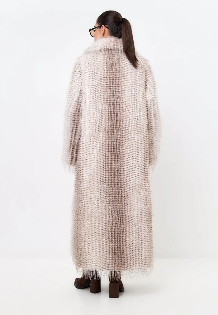 A stylish woman wearing a long, belted faux fur coat perfect for winter fashion.