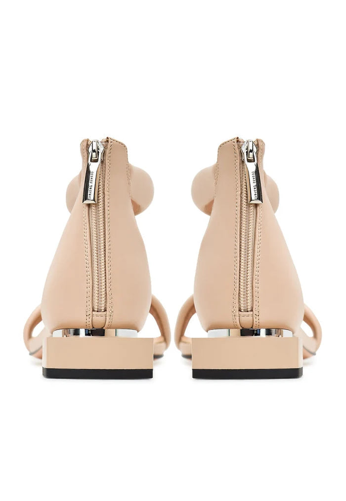 A stylish pair of beige block heel sandals worn by a woman named Sofia, perfect for any summer outfit.