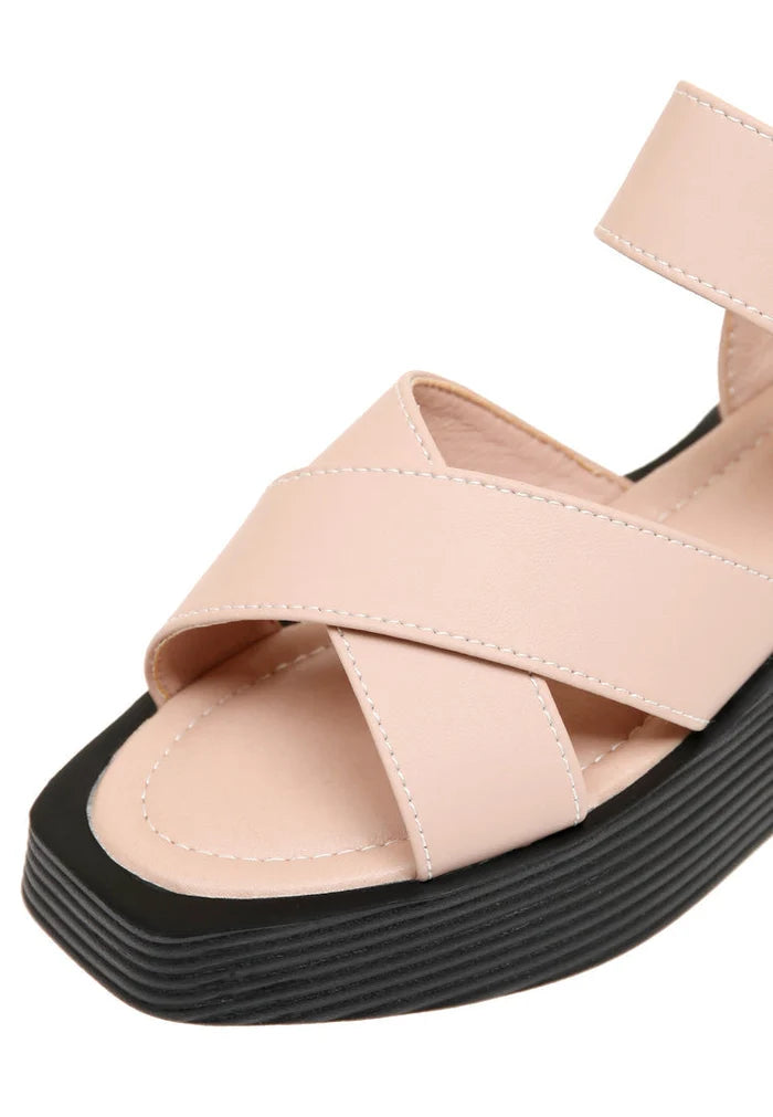 A pair of stylish women's platform sandals in blush pink with strappy details and high heels.