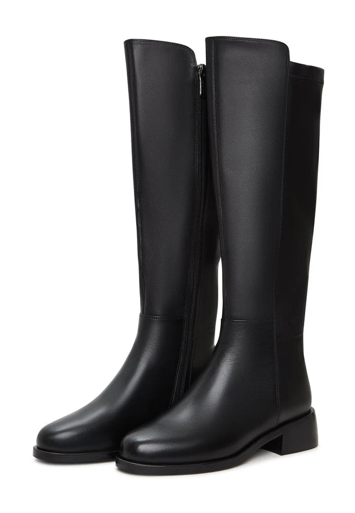 A fashionable woman wearing classic black leather knee-high boots, a must-have for any stylish wardrobe.
