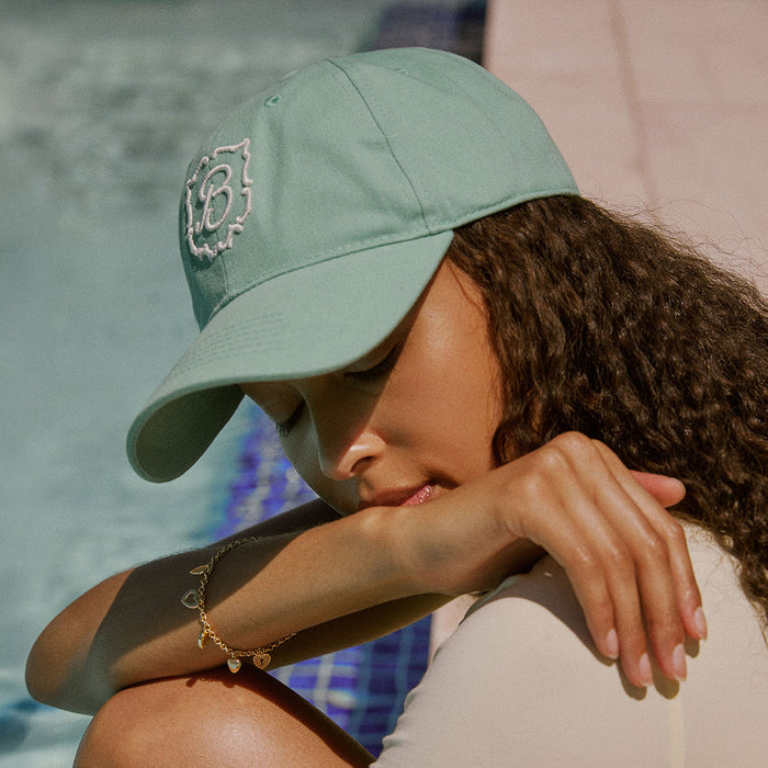 Front three-quarter view of Retro Crest Cap in Lido cotton showcasing embroidered crest logo and curved brim with model by pool