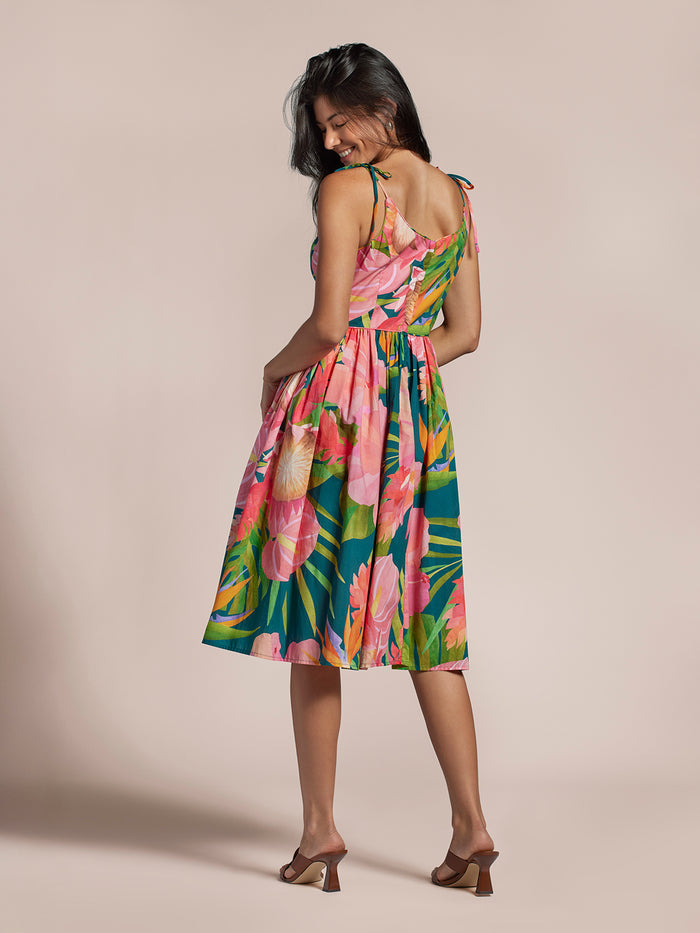Woman smiling in multicolor art deco floral-print Carmela dress, back view.