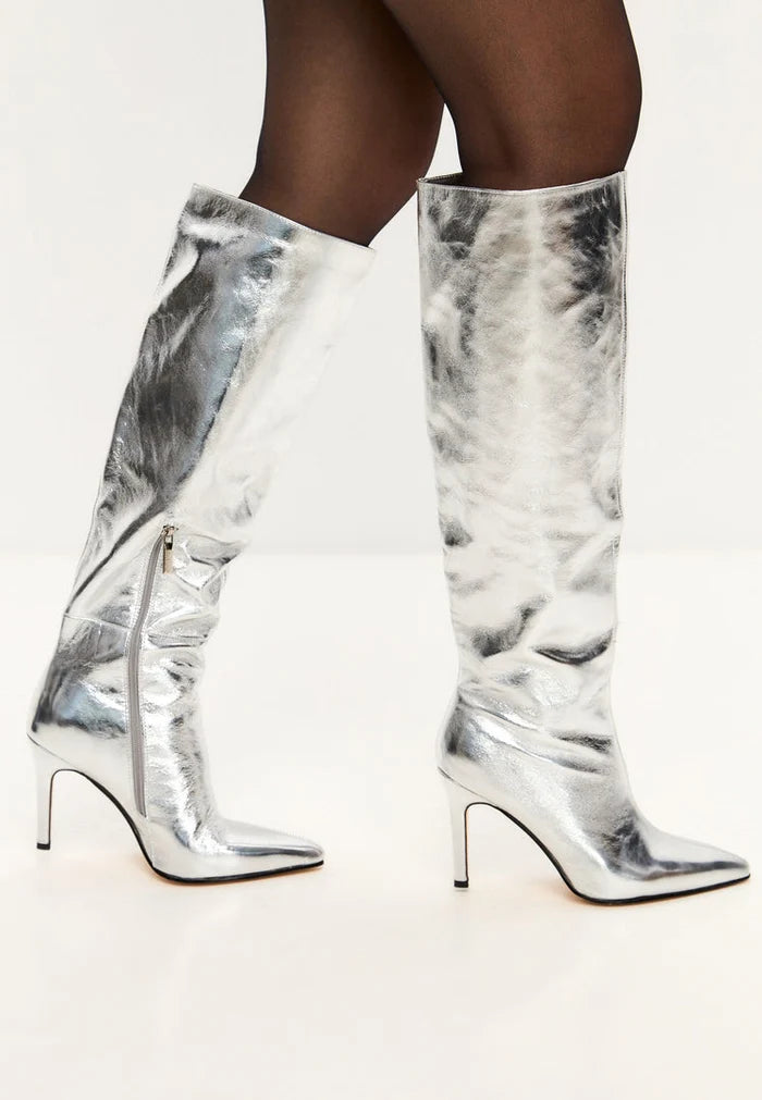 A fashionable pair of silver knee-high metallic high heel boots, the perfect trendy statement footwear for an elegant look.