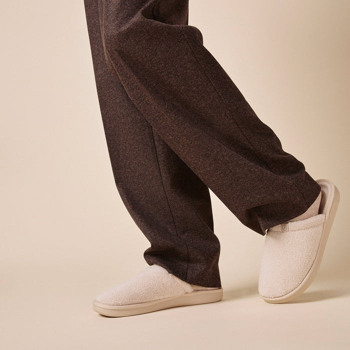 Side view of Essential terry slipper in beige showcasing plush terry upper and cushioned low-profile sole against a neutral studio background