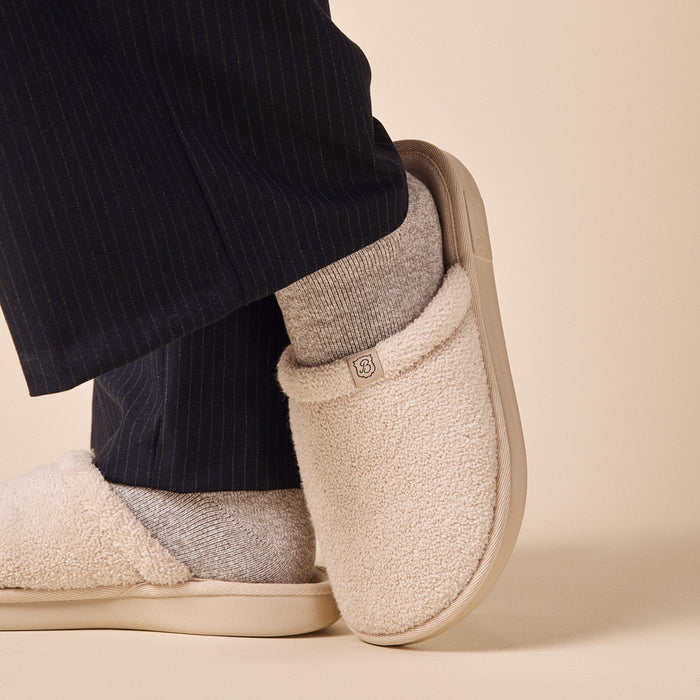 Side view of Essential Terry slipper in beige showing textured terry upper and cushioned beige outsole on a neutral background