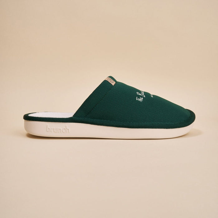 Side view of green Essential slipper with embroidered Beverly Hills Hotel logo and white EVA sole on beige background