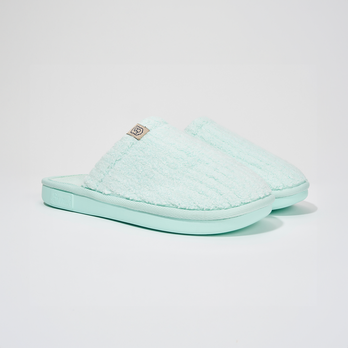 Angled view of Lido Essential slipper in aqua showcasing ribbed terry upper, low open-back silhouette, and cushioned foam sole on white background