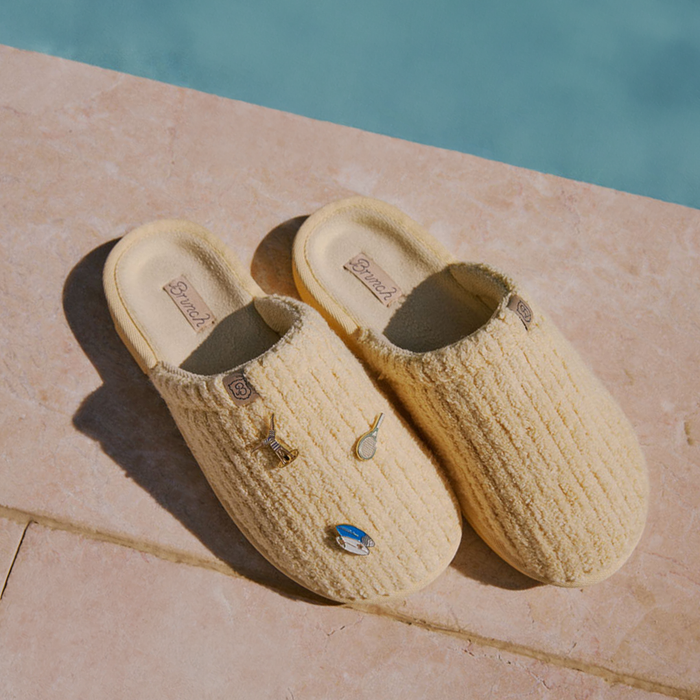 Angled top-down view of Limoncello ribbed terry slipper showing ribbed texture and magnetic charms on a stone ledge