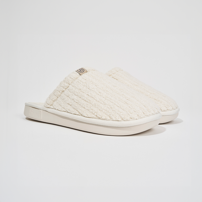 Angled side view of The Essential slipper in Panna ribbed terry showing plush ribbed upper and EVA outsole on white background
