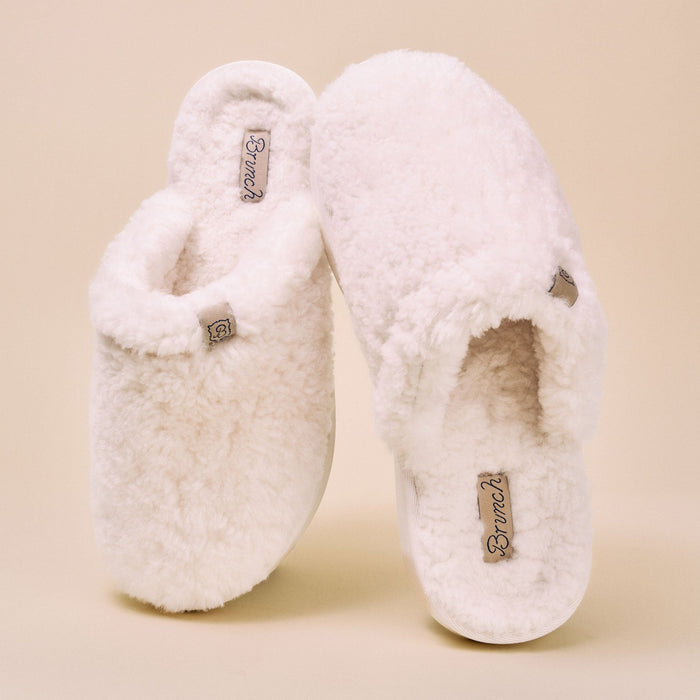 Front-facing pair of Essential All Shearling slippers in natural showcasing plush all-shearling upper and lining with warm beige studio background