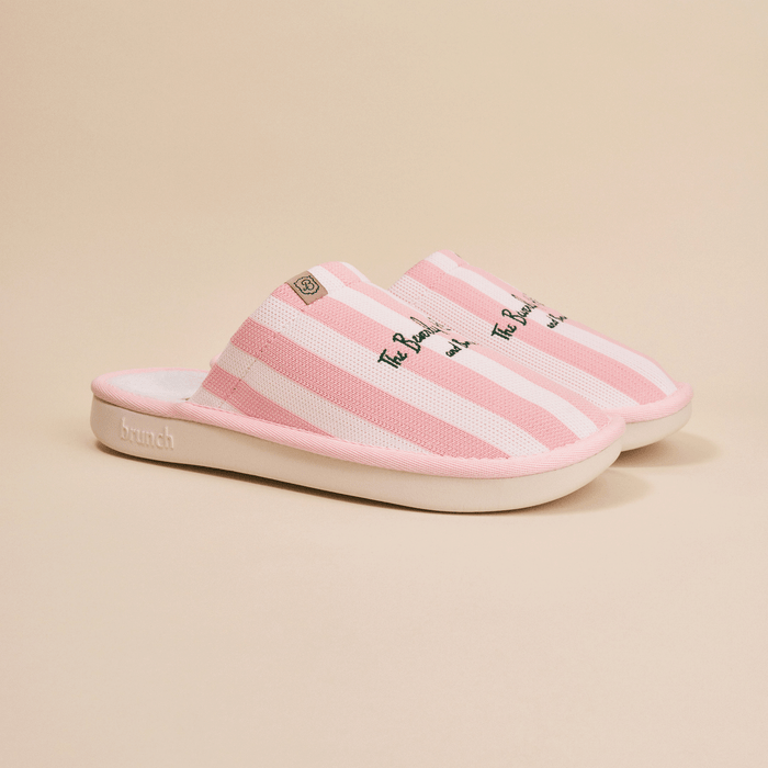 Side view of Essential slipper in pink and white stripes, embroidered Beverly Hills Hotel text, open-back mule with cushioned white sole on beige background
