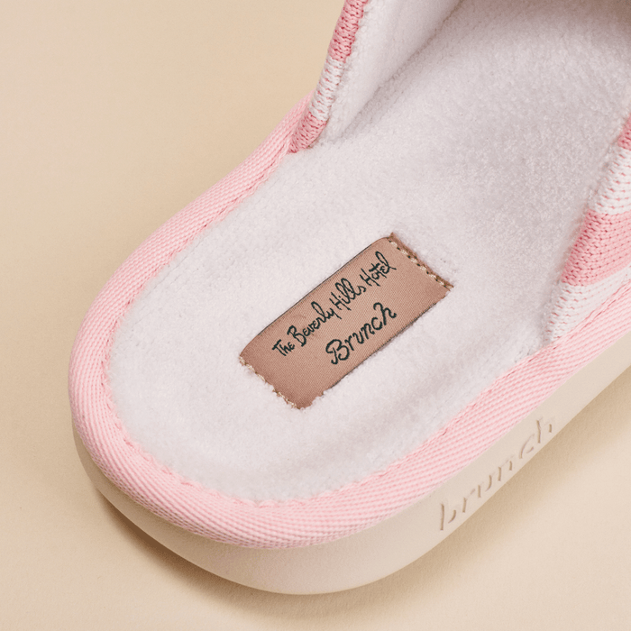 Close-up of pink Essential slipper showcasing fleece footbed and sewn label The Beverly Hills Hotel Brunch on beige background
