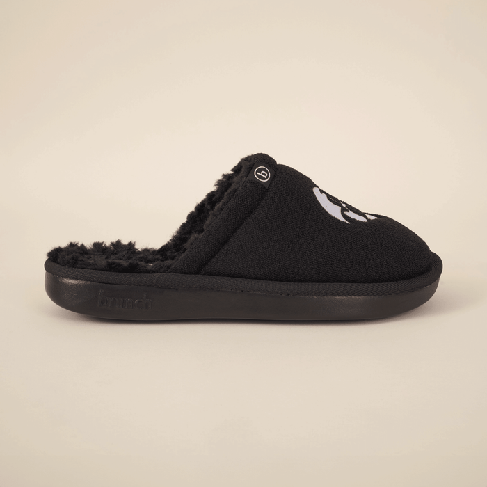 Side view of black Diet Coke x Brunch slipper with faux shearling lining and embroidered logo on beige background