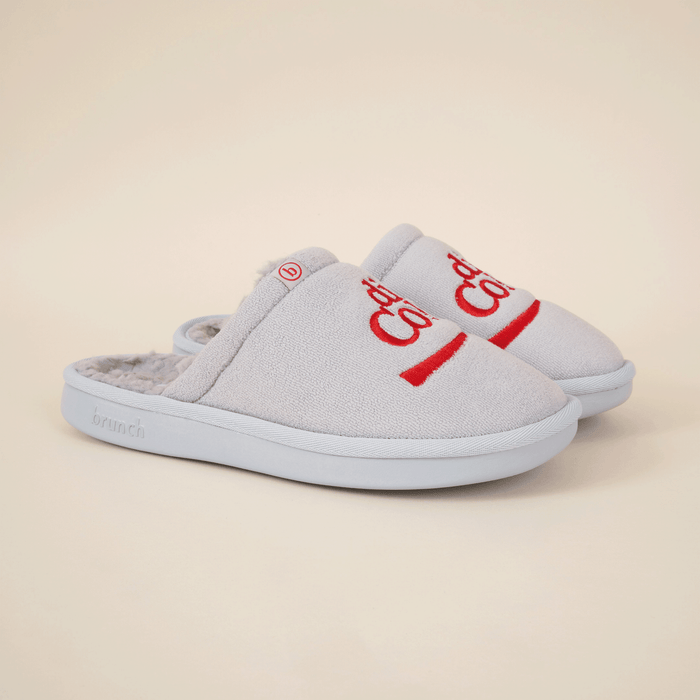 Angled view of grey Diet Coke collab slippers with red embroidered logo, faux shearling lining and molded sole