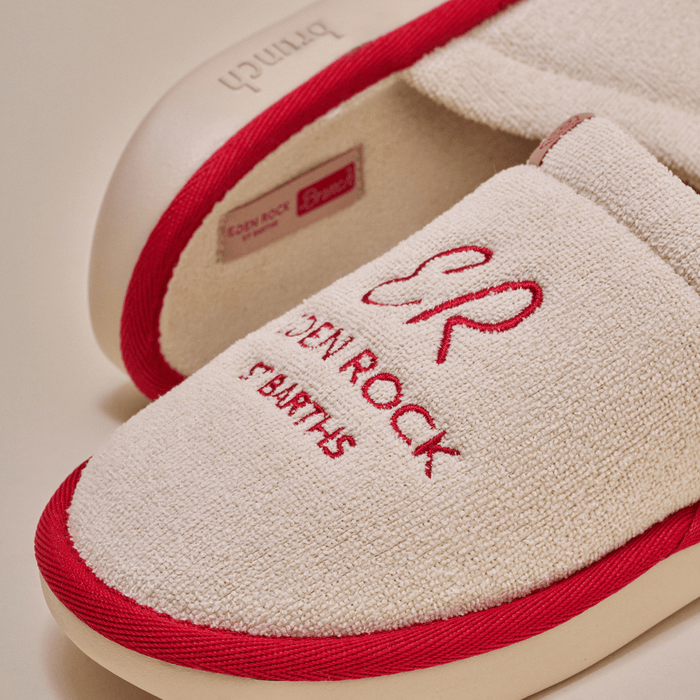 Close-up of beige Eden Rock slipper showcasing red embroidered Eden Rock St Barths logo and red trim on terry upper