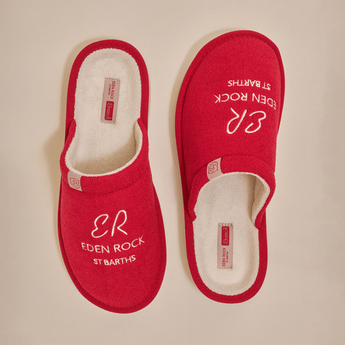 Top view of red Eden Rock slippers with ER Eden Rock embroidery and cream terry lining on beige background