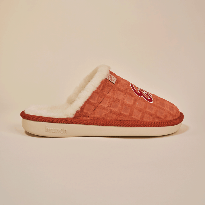 Side view of Essential Eggo slipper in syrup with waffle-embossed suede upper, shearling lining and cream outsole on neutral background