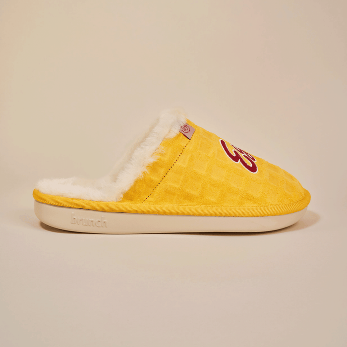 Side view of yellow Essential Eggo slipper showing waffle-embossed suede upper, white shearling lining, and cream outsole