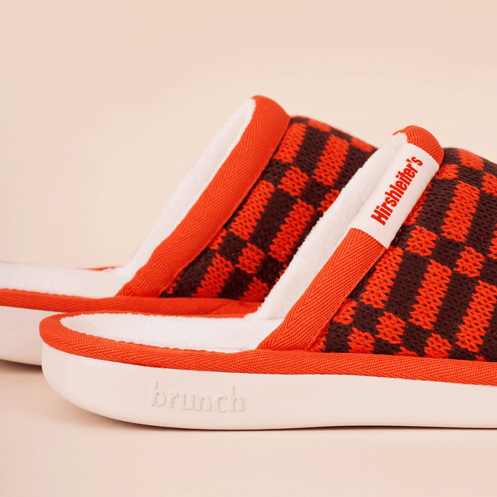 Side view of Amber knit slipper with orange and brown pattern, white terry lining, Hirshleifer's tag and embossed brunch sole