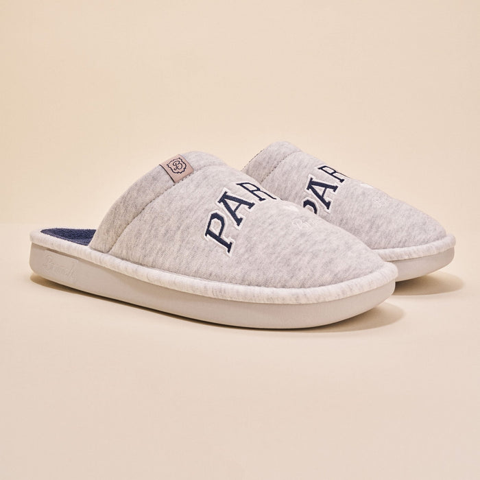 Angled view of pair of Essential Parke Varsity fleece slippers with embroidered PARKE lettering, cushioned white sole on beige