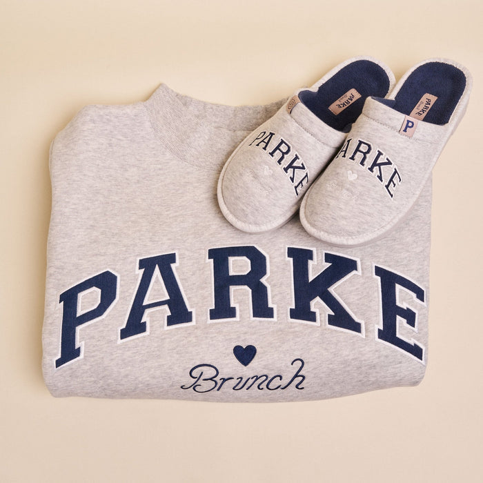 Folded Parke mockneck fleece in classic grey with navy PARKE lettering and Brunch embroidery, with matching slippers on cream