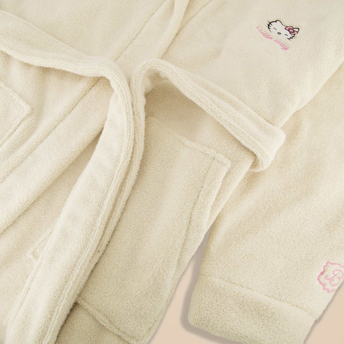 Close-up of Essential Robe in cream showing terry texture, hood, pocket and Hello Kitty embroidery on a neutral background