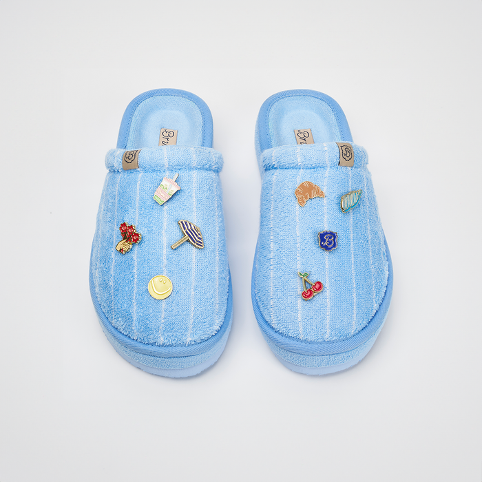 Top-down view of Essential XXL slippers in Cabana blue striped terry showcasing attached magnetic charms on a white background