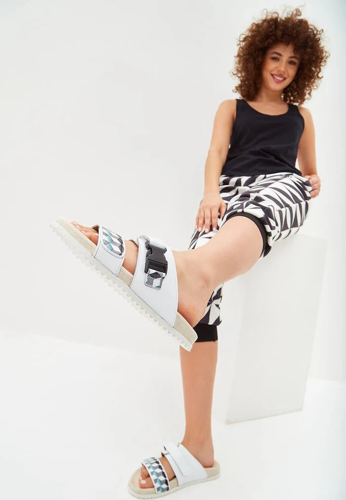 A pair of stylish white Meredith mules with a flat sole, perfect women's footwear for the summer season.