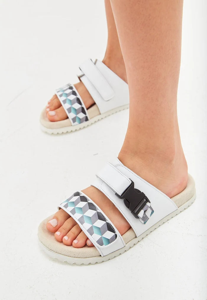 A close-up image of white Meredith mules, stylish flat sole summer sandals for women's footwear.