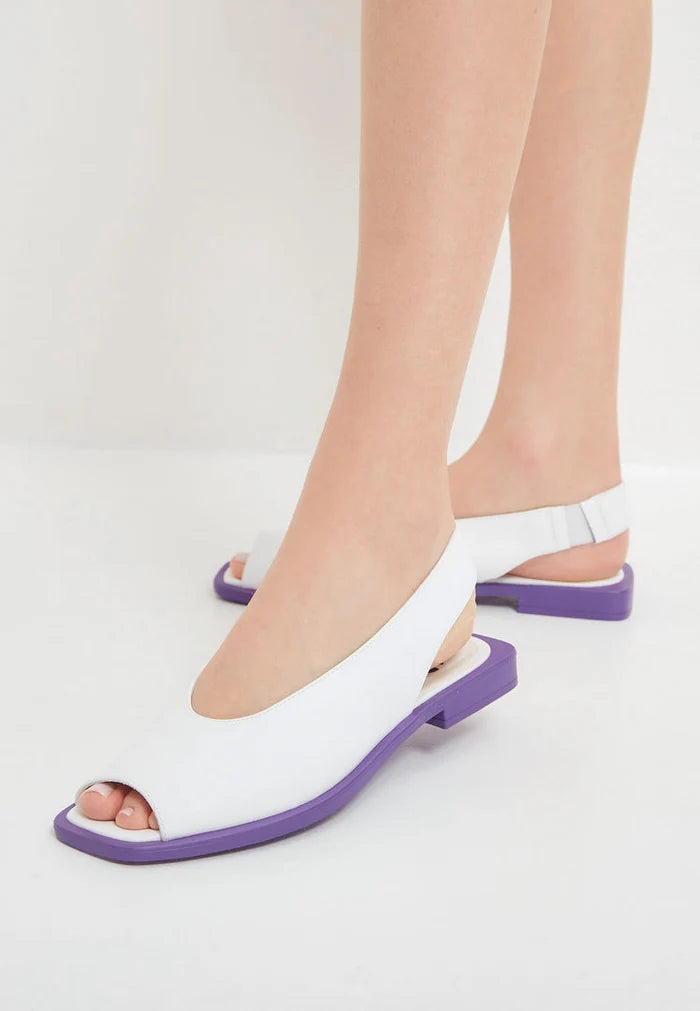 A pair of trendy white women's flat sole sandals, perfect for summer. These casual sandals are the ideal choice for any warm-weather outfit.