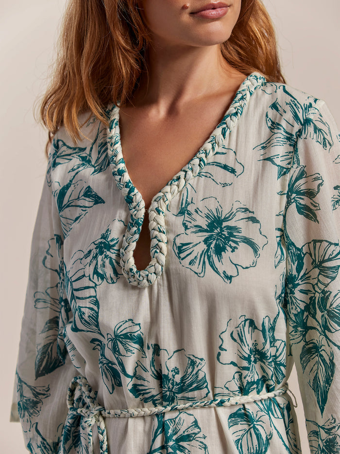 White cotton midi dress with green floral print and braided trim, front and side views.