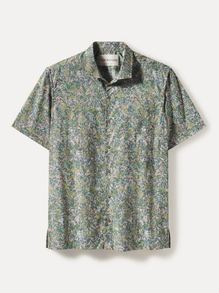 White short-sleeve shirt with green and purple leaf print; white cotton Hawaiian shirt, leaf pattern, flat lay.
