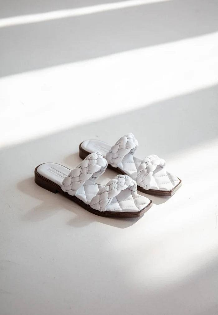 A stylish pair of white soft leather flat sole sandals, offering high quality craftsmanship and ultimate comfort for all-day wear.