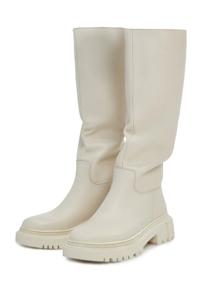 A woman wearing stylish knee-high leather boots in the color Anastasia beige, the perfect addition to any women's fashion wardrobe.