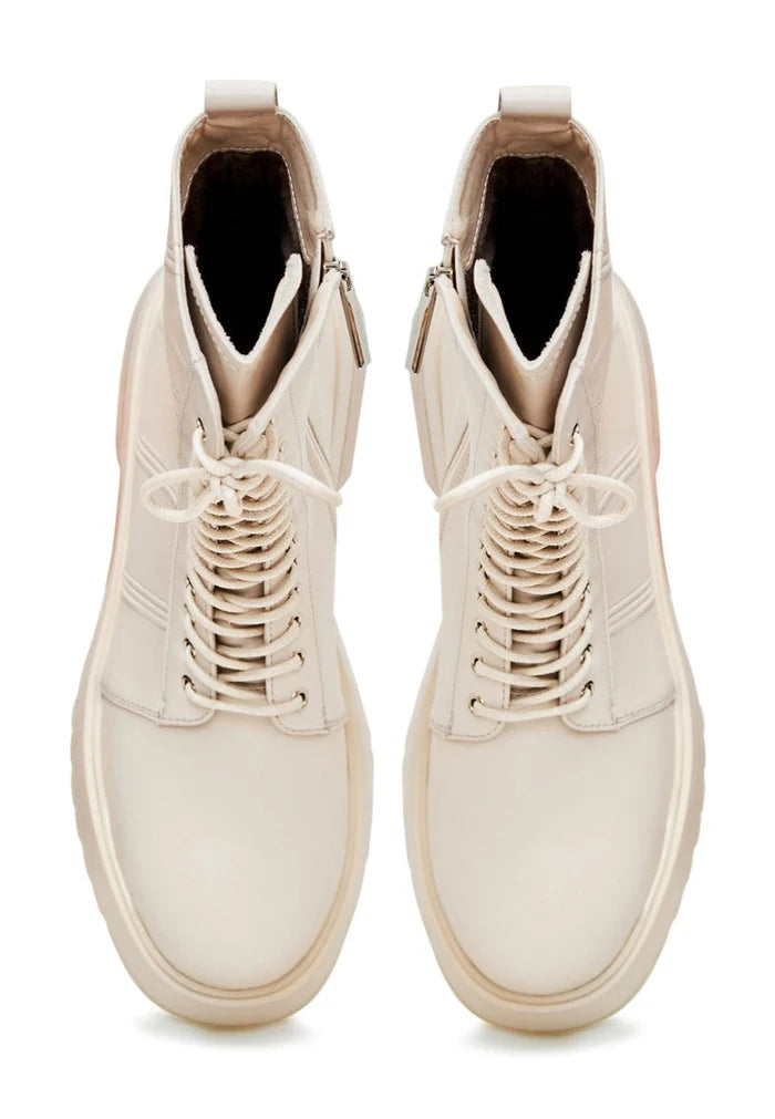 A fashionable pair of lace-up leather ankle boots in beige for women, perfect as stylish fashion boots.