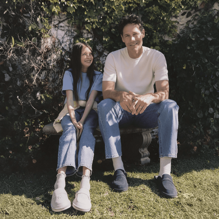 Young girl and man sitting on a garden bench wearing cream and navy suede Yankees loafers