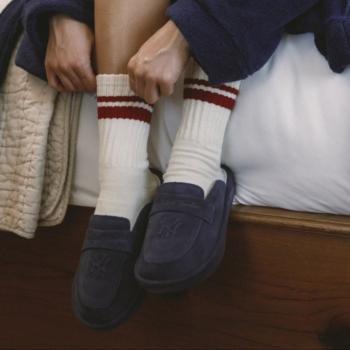 Front close-up of navy suede Yankees loafer showcasing embossed Yankees crest and suede texture, worn with white crew socks