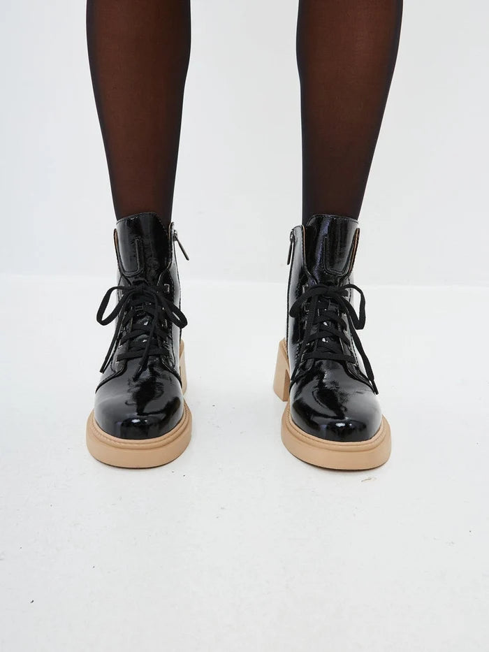 A stylish pair of black patent leather ankle boots with lace-up details, perfect for women seeking patent leather footwear options.