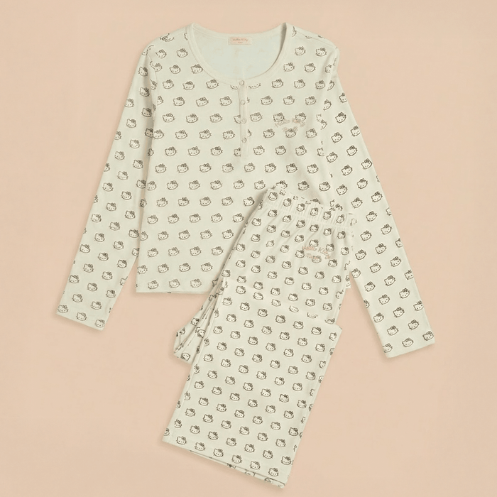 Flat lay of cream Hello Kitty cotton pajamas, long-sleeve button top and elastic-waist pants on pale pink background