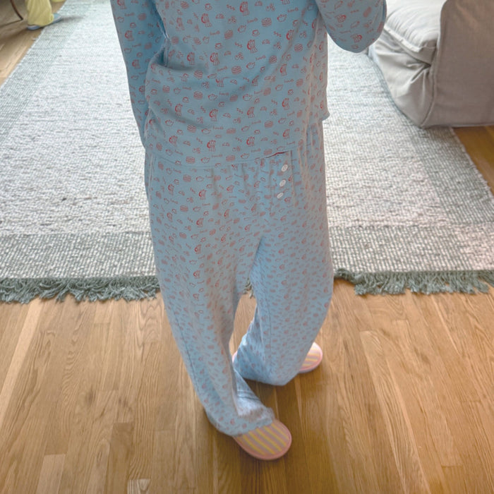 Front view of French Blue Cozyland pajama set with small pink print and relaxed wide-leg pants with button fly on hardwood floor
