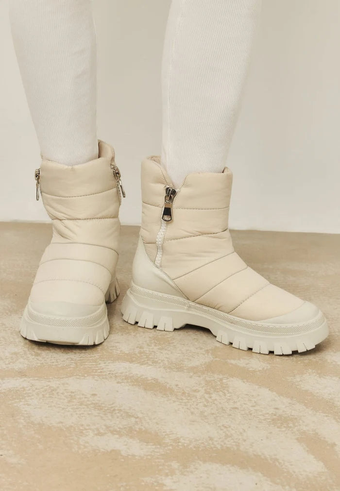 A stylish pair of women's winter fashion boots in beige color with a trendy platform design.