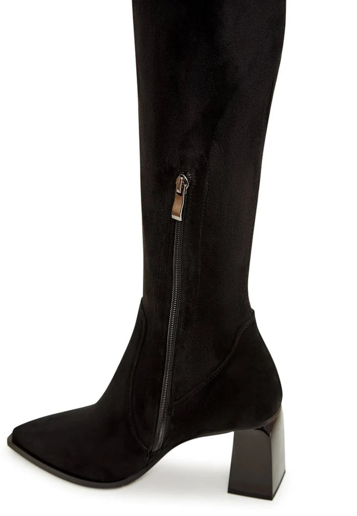 A stylish woman wearing over-the-knee suede boots, a chic and fashionable choice in women's footwear.