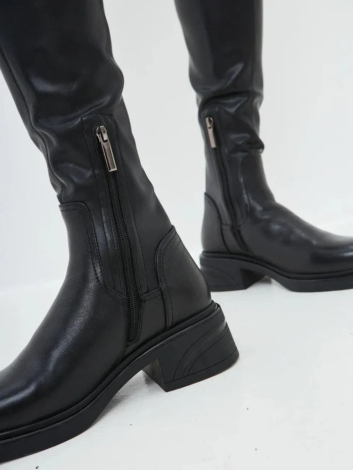 A stylish woman wearing chic over-the-knee suede boots, the latest fashion trend in women's footwear.