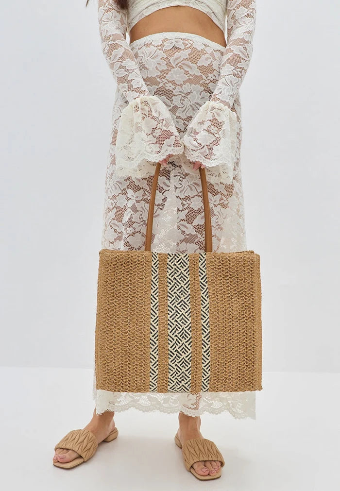 Stylish white and blue striped summer tote bag with colorful tassels, perfect for a day at the beach.